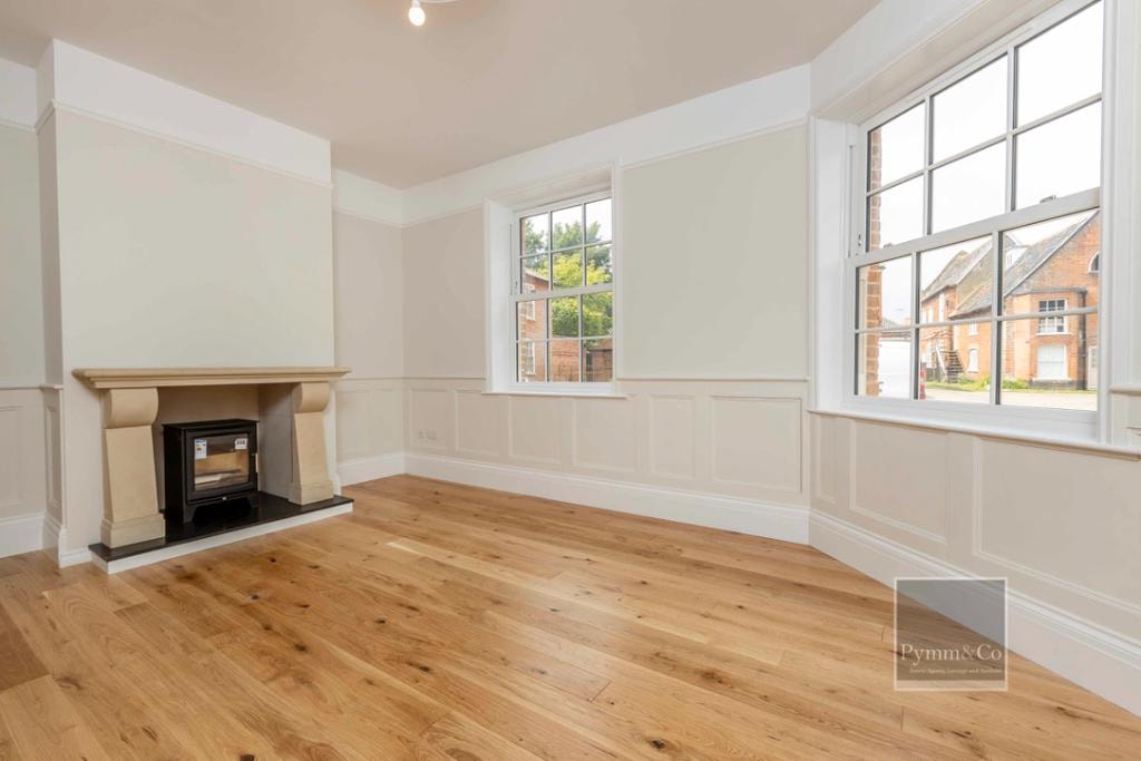 Malthouse refurbishment — reception room with oak flooring, panelled walls, log burner and sash windows
