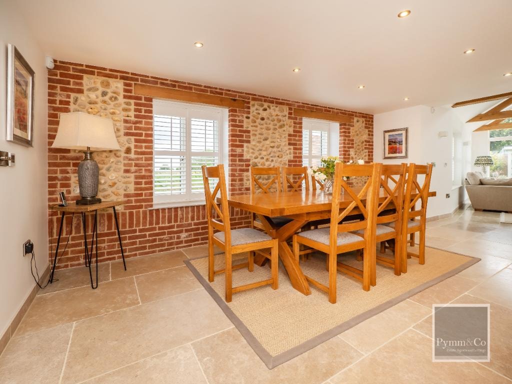 Orchard Cottage — dining room with exposed brick and flint wall, oak table and travertine floor