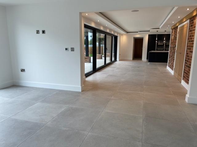 The Nook — open-plan living space with large format floor tiles and bifold doors to garden